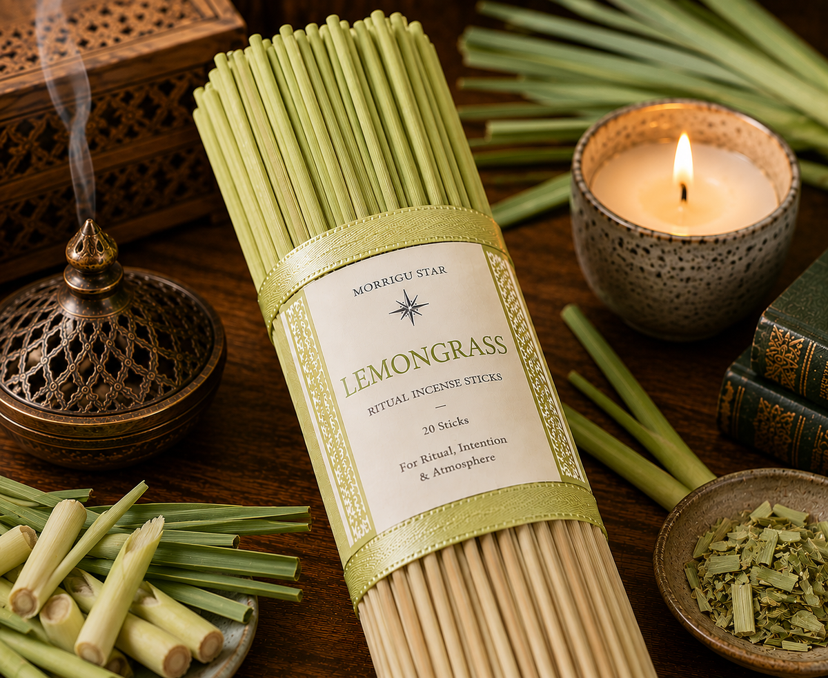 A bundle of  Morrigu Star Lemongrass ritual incense sticks in a paper sleeve with a green ribbon, styled on a dark wooden table with a lit candle, incense burner, fresh lemongrass, and books.